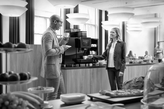 Two people talking over coffee at a campus common area